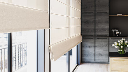 Moderne Raffrollos in warmen Naturtönen an bodentiefen Fenstern in einer stilvollen Küche mit dunklen Schränken und Holzelementen.