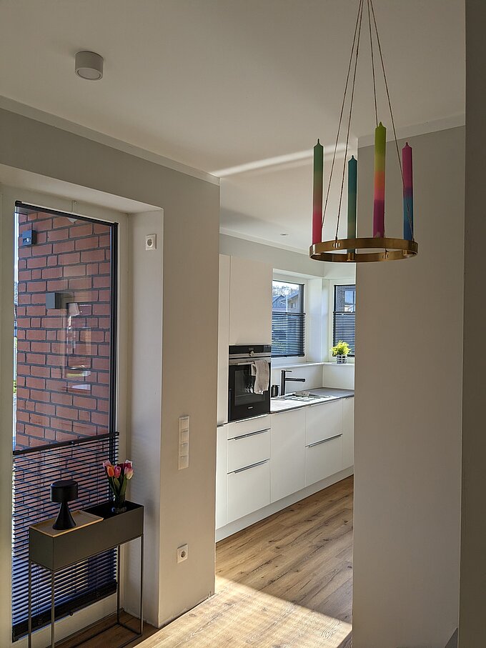 Blick vom Flur in eine moderne Küche mit mehreren Fenstern, alle mit Twinline-Jalousien ausgestattet.