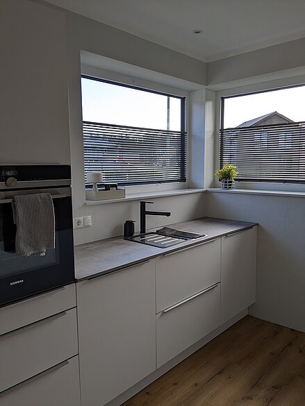 Moderne Küche mit zwei Fenstern, in denen Twinline-Jalousien zur Lichtregulierung montiert sind.