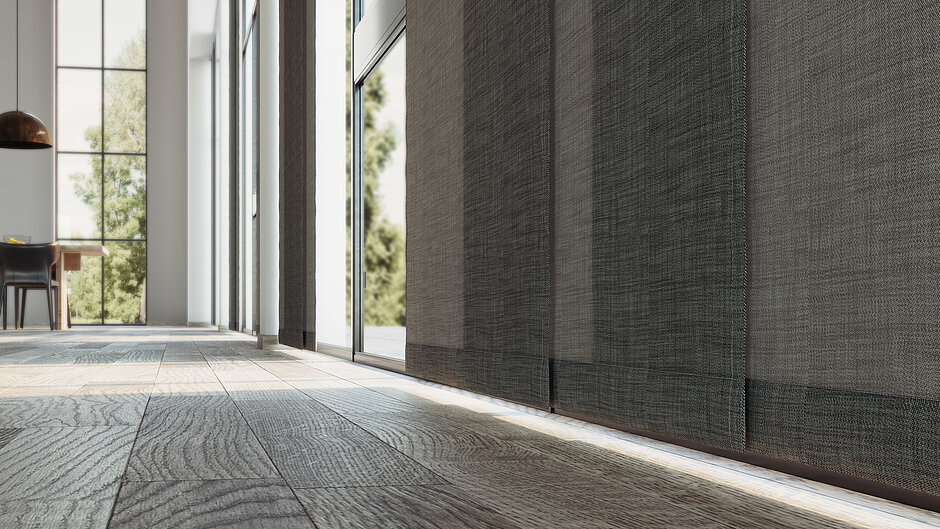 Nahaufnahme eines dunkel strukturierten Flächenvorhangs an einem grossen Fenster mit sichtbarer Stofftextur und Schattenwurf.