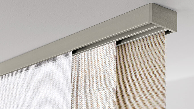 Helle MHZ Vorhangschiene „Carat 24“ mit drei Flächenvorhängen in unterschiedlichen Texturen.