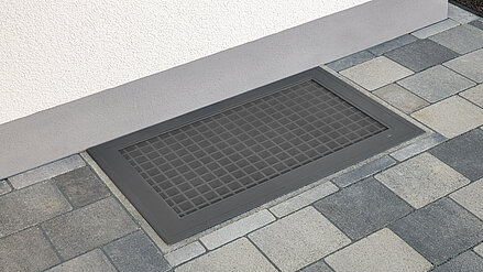 Lichtschachtabdeckung mit integriertem Edelstahlgitter vor einer Hauswand installiert.