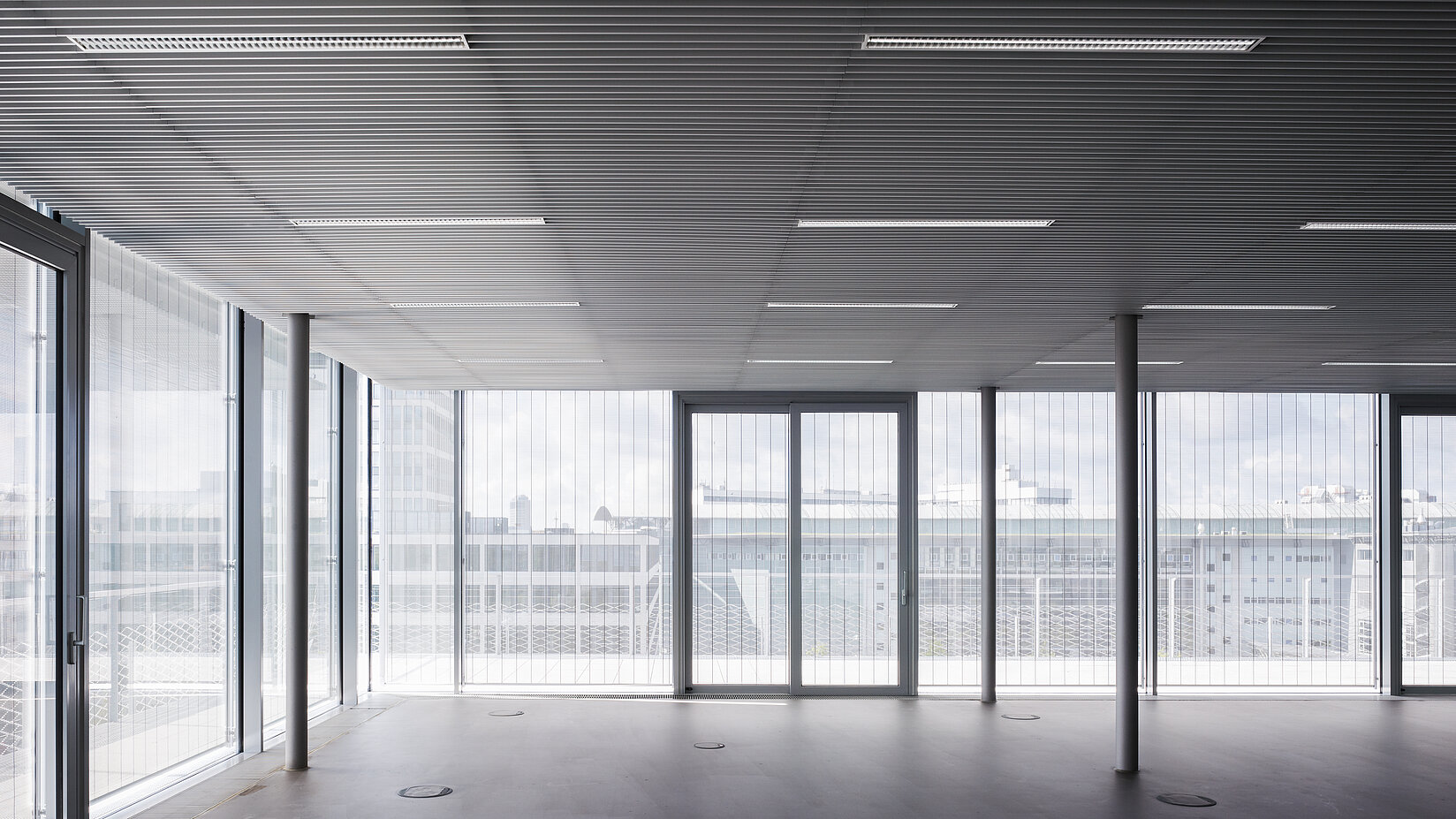Moderner, leerer Büroraum mit MHZ-Metallbehang an grossen Fensterflächen.