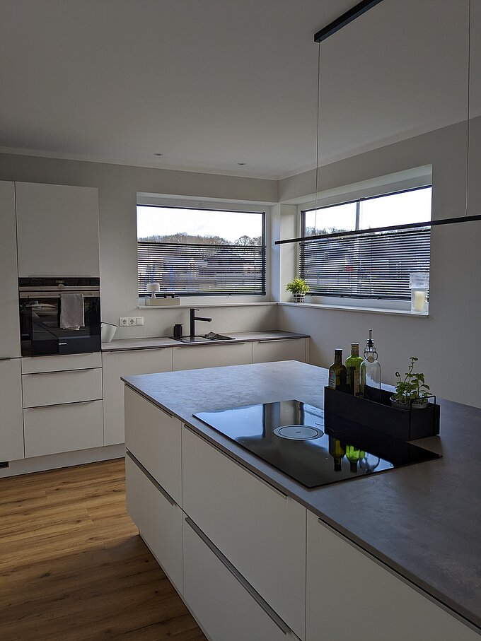 Moderne Küche mit Eckfenstern, ausgestattet mit Twinline-Jalousien zur Lichtregulierung und Sichtschutz.