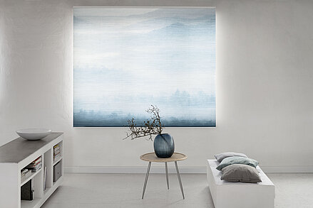 MHZ Wabenplissee mit sanftem Landschaftsmotiv in Blau, vor einem hellen Raum mit minimalistischer Einrichtung.