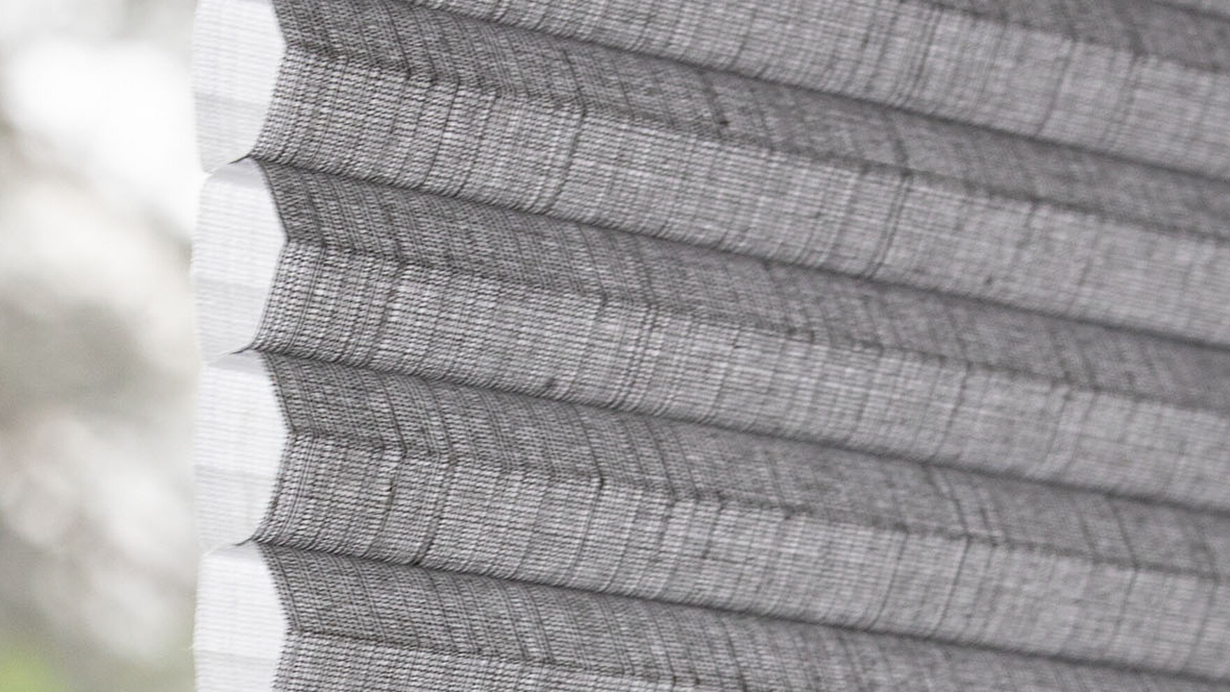 Gros plan latéral d'un store plissé nid d’abeilles MHZ gris avec une structure cellulaire clairement reconnaissable.