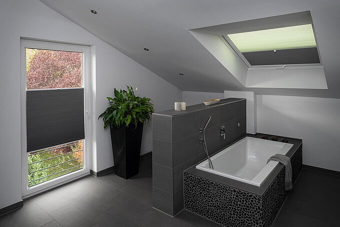 Badezimmer mit grauer Fliesengestaltung, ausgestattet mit Wabenplissees an Dach- und senkrechtem Fenster